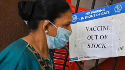 Getty Images 2021/04/08: A woman wearing a facemask as a precaution against the spread of covid-19 seen reading a poster saying 'vaccine out of stock' outside a vaccination center in Mumbai