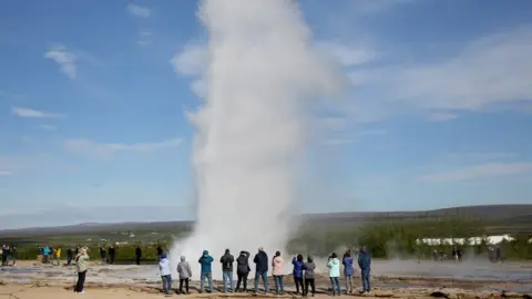 EPA Tourists stand around a Geyser in Iceland