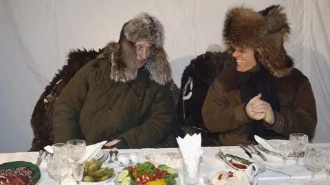 ITAR-TASS/AFP via Getty Images Putin and Berlusconi in warm winter outfits on a trip to a wildlife preserve north of Moscow in 2003