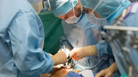 BSIP/Getty Images Surgeons in operating theatre