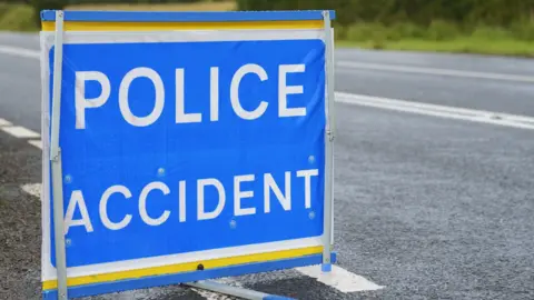 A blue and white "police accident" sign on an empty road.