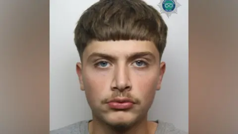 A man with short brown hair and a faint moustache