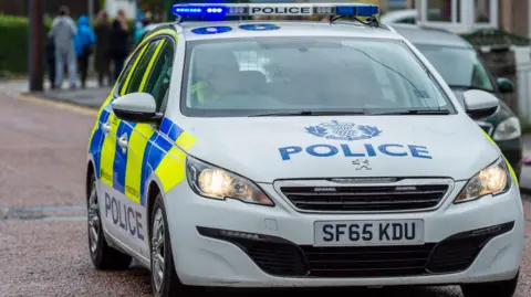 Getty Images A police car with the word police in blue writing across the bonnet.