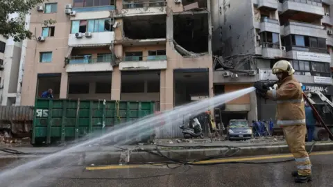Reuters Hezbollah-affiliated civil defence member sprays water at a damaged site in the aftermath of what security sources said was an Israeli drone strike in Beirut's southern suburb of Dahiyeh, Lebanon (03/01/24)