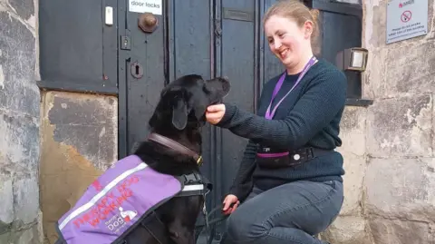 De Montfort University Woman stroking black labrador dog
