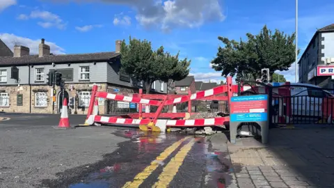 Water leaking from a hole which has been cordoned off on a main road