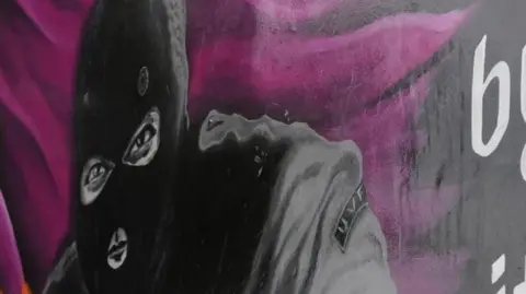 Mural of a man in a balaclava with purple background