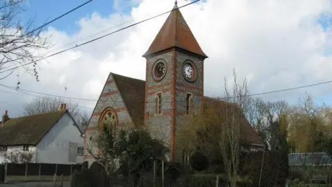 Stewart Village Hall in Brightwell-cum-Sotwell, Oxfordshire. It is a large grey and red building with a clocktower.