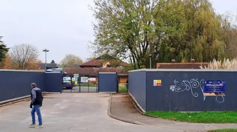 LDRS The site of the former Three Counties Hotel. It is boarded off with blue boards as a man walk past the entrance.