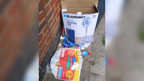 Fly tipped items including a crisp box, litter and fan box