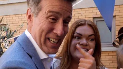 Shaun Whitmore/BBC Fran, who has long auburn hair, pointing excitedly at Anton Du Beke. They are outside, with some blue bunting visible.