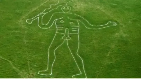 National Trust Green grassy hill with giant chalk figure - the Cerne Abbas Giant - carved into it.