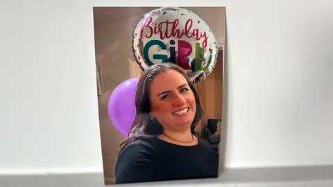 A woman with long hair and a birthday balloon