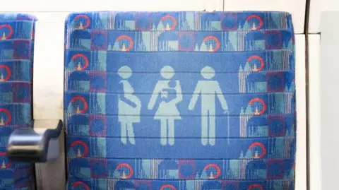 Getty Images A blue priority seat on a London Underground train featuring icons of a pregnant person, a person carrying a child, and a person with a walking stick.