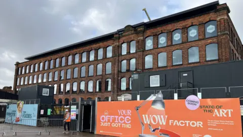 Grade II-listed Eckersley Mill in Wigan was built in 1884.  It is a large, symmetrical, rectangular building with four storeys. There are large windows with round arches at the top of each of them.