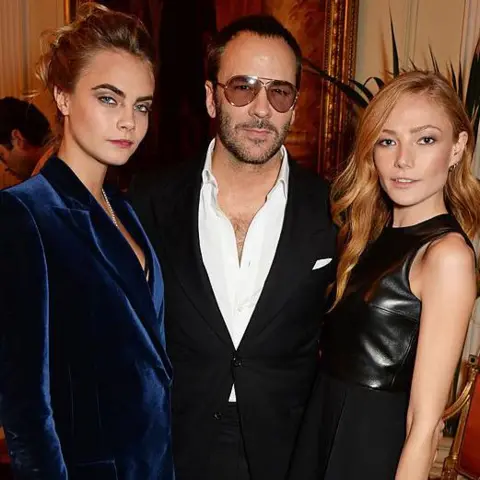 David M. Benett/Getty Images Two women stand with a man in between them, they are all facing the camera