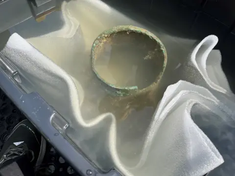 The top of the ship's bell in a large container of seawater