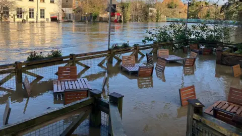 Tables and chairs outside a restaurant submerged in flood water