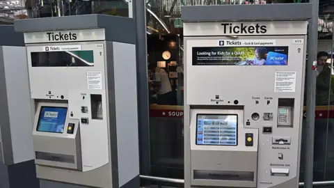 Getty Images Two large grey ticket machines at a train station.