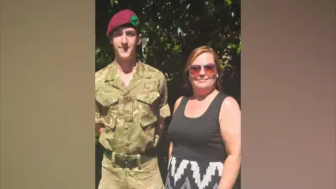 Handout Pte Harry Johnson, pictured in army uniform, with his mother Rowen, who has red hair and is wearing sunglasses.