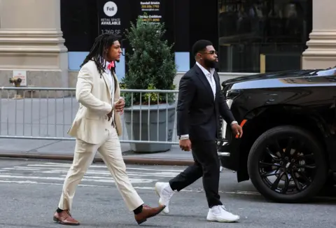 Reuters NFL athlete Isiah Pacheco arrives at Madison Square Garden wearing a cream suit and tan shoes.