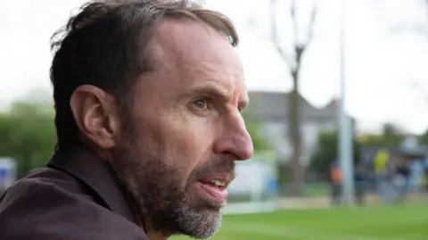 Sir Gareth Southgate beside a football pitch