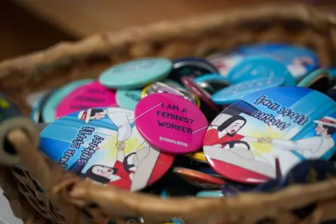 Badges with the slogan "I am a feminist worker" on them