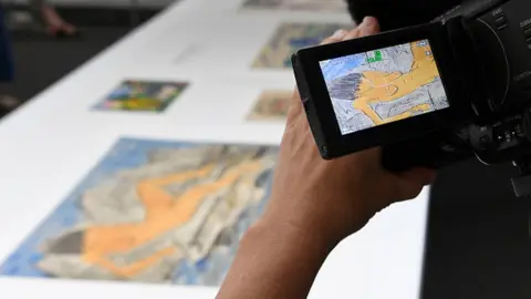 AFP A journalist films the 'Liegende weiblicher Akt am Wasser' an aquarelle by German expressionist Otto Mueller and coming from the estate of German collector Cornelius Gurlitt during a press preview of the first masterpieces of the estate of Gurlitt at the Museum of Fine Arts Bern (07 July 2017)