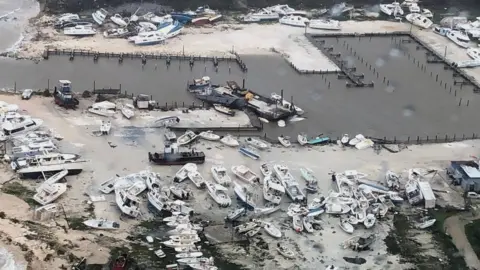 EPA/US COAST GUARD HANDOUT An aerial photo of a harbour with many boats pushed out of the sea and destroyed