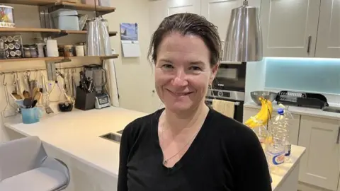 A woman smiling in her kitchen. 