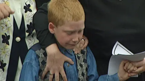 BBC Seven-year-old Louie Johnston cries as he walks behind his father's coffin