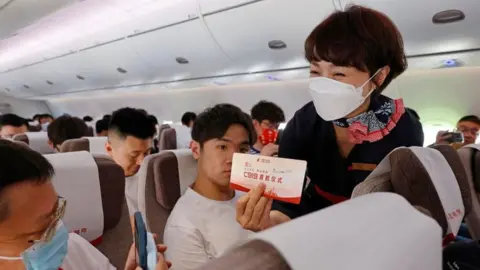 A passenger takes photos of a card during the first commercial flight of China's first domestically produced passenger jet C919