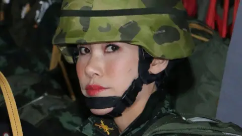 Reuters Sineenat wears full military camouflage and a helmet while seated in a plane