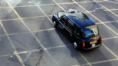 Image of black London cab in yellow cross box