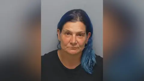 Hampshire Constabulary /PA Images Sarah Johnson is looking at the camera in a police custody photo. She has shoulder-length dyed blue hair and piercings in her nose, ears and eyebrow.