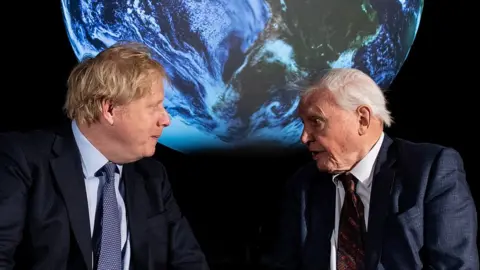 Getty Images Boris Johnson and David Attenborough talking in front of a projection of Earth