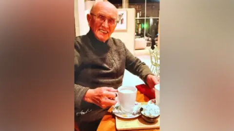 An older man sitting drinking a hot drink in a cafe