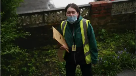 Catherine McGuinness Cath is wearing a facemask as she delivers a parcel to someone's house