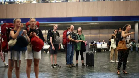 Reuters People look at departure information screens at Euston railway station
