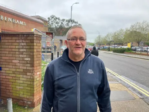 Matt Marvel/BBC David wearing a blue jacket, black t-shirt. He is standing on the pavement.