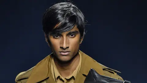 Getty Images 20-year-old Jeenu Mahadevan wears a brown trenchcoat as he models for Givenchy at Paris Fashion Week in 2018