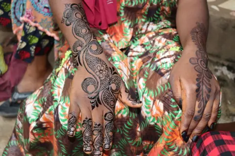 Getty Images A woman shows her hands painted with henna, in Yaounde, Cameroon on December 30, 2022. Muslims in Cameroon show their happy moments such as weddings, religious holidays, reciters of the Qur'an and hafiz ceremonies with henna paintings applied on their bodies. Henna is made from dried up henna tree leaves, after the leaves turned into powder, water and oil are added; also some plants can be added to the henna applied in this state to obtain different colors upon request