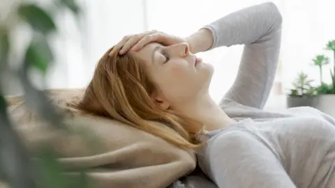 Getty Images young woman lying down with hand on her head