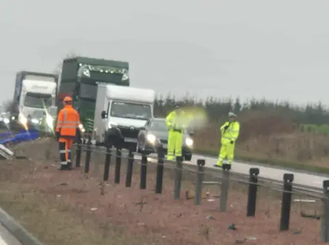 Iona Young People in high vis clothing in front of a queue of traffic on a dual carriageway