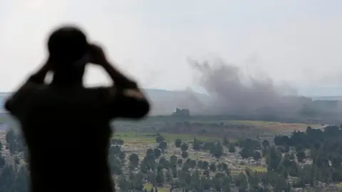EPA A Turkey-backed Free Syrian Army soldier watches with binoculars as smoke rises after a bomb attack during an offensive, at Der Mismis Village, southeast of Afrin, Syria.