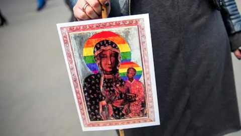 Getty Images A protester holds a poster showing the Virgin Mary and child with rainbow halos