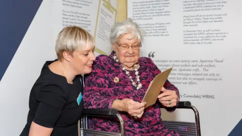 Mark Fraser Photography Joanna Chorley looking at her certificate with carer Amanda Siviter, Recreation and Activities Co-ordinator at her care home Tewkesbury Fields