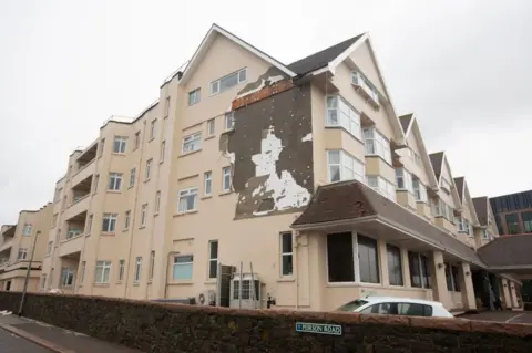 Getty Images The Grand Hotel shows signs of damage, with the side rendering ripped, away after winds reaching 100 mph tore through the island in the early hours of the morning on November 2, 2023 in St Helier,