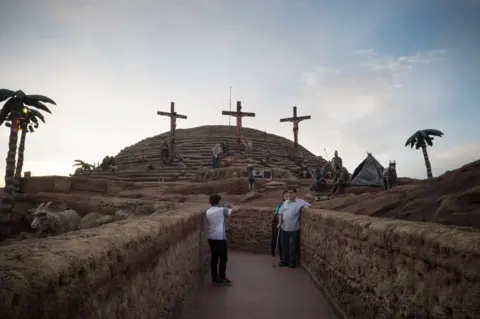 Erica Canepa Tourists take photographs in front of three crucifixes