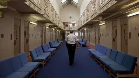 Getty Images A female prison officer walks through the communal area inside HM Prison Styal in Cheshire